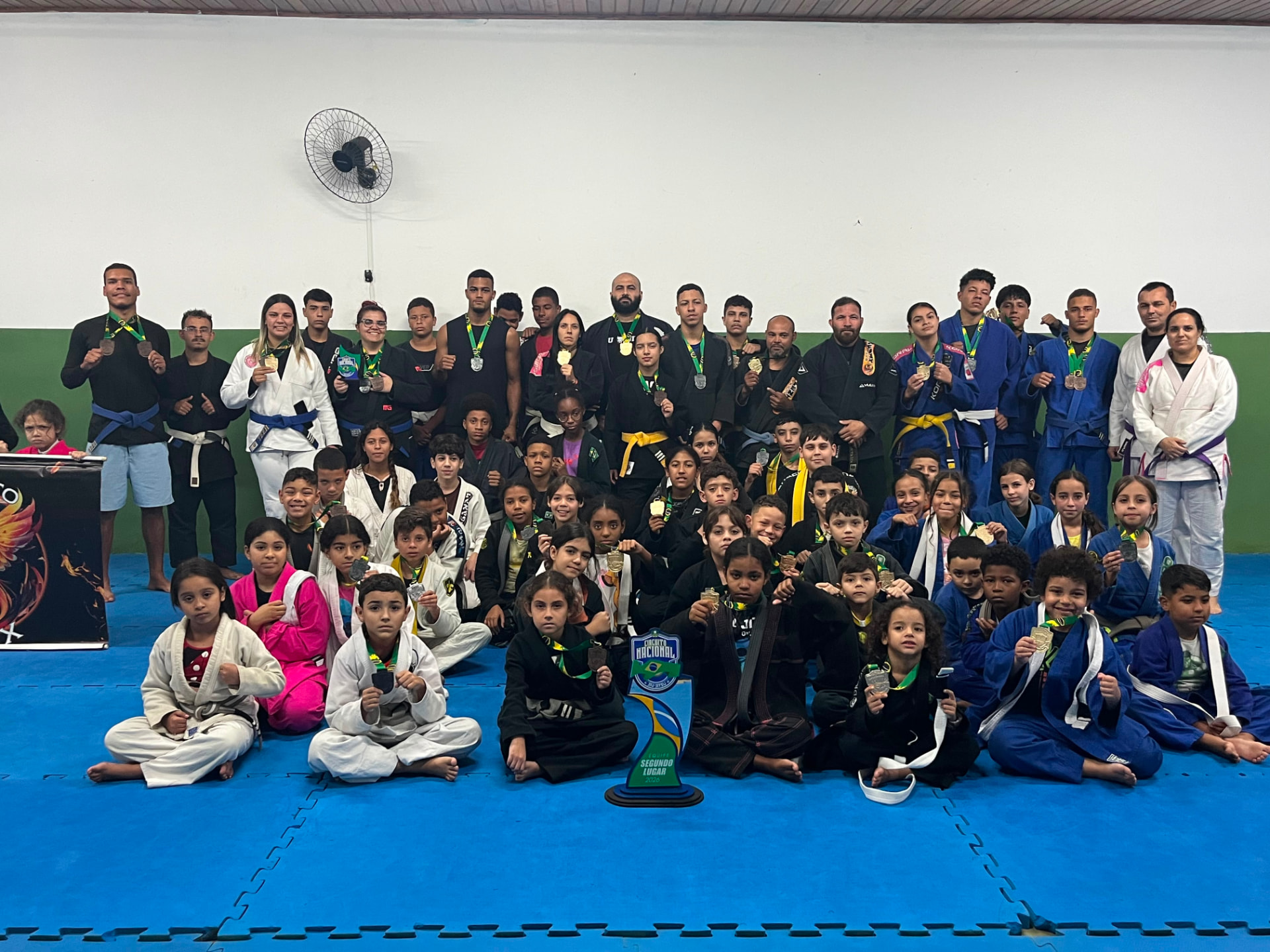 Equipe Projeto Fênix reunida no tatame com medalhas e troféu de segundo lugar