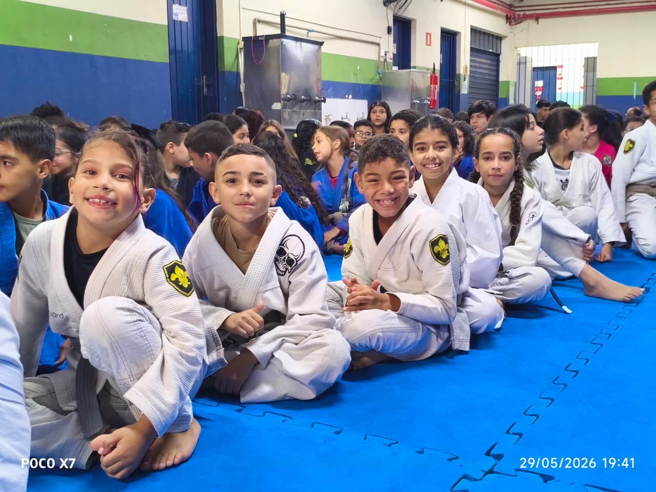 Crianças sorrindo lado a lado durante cerimônia no tatame