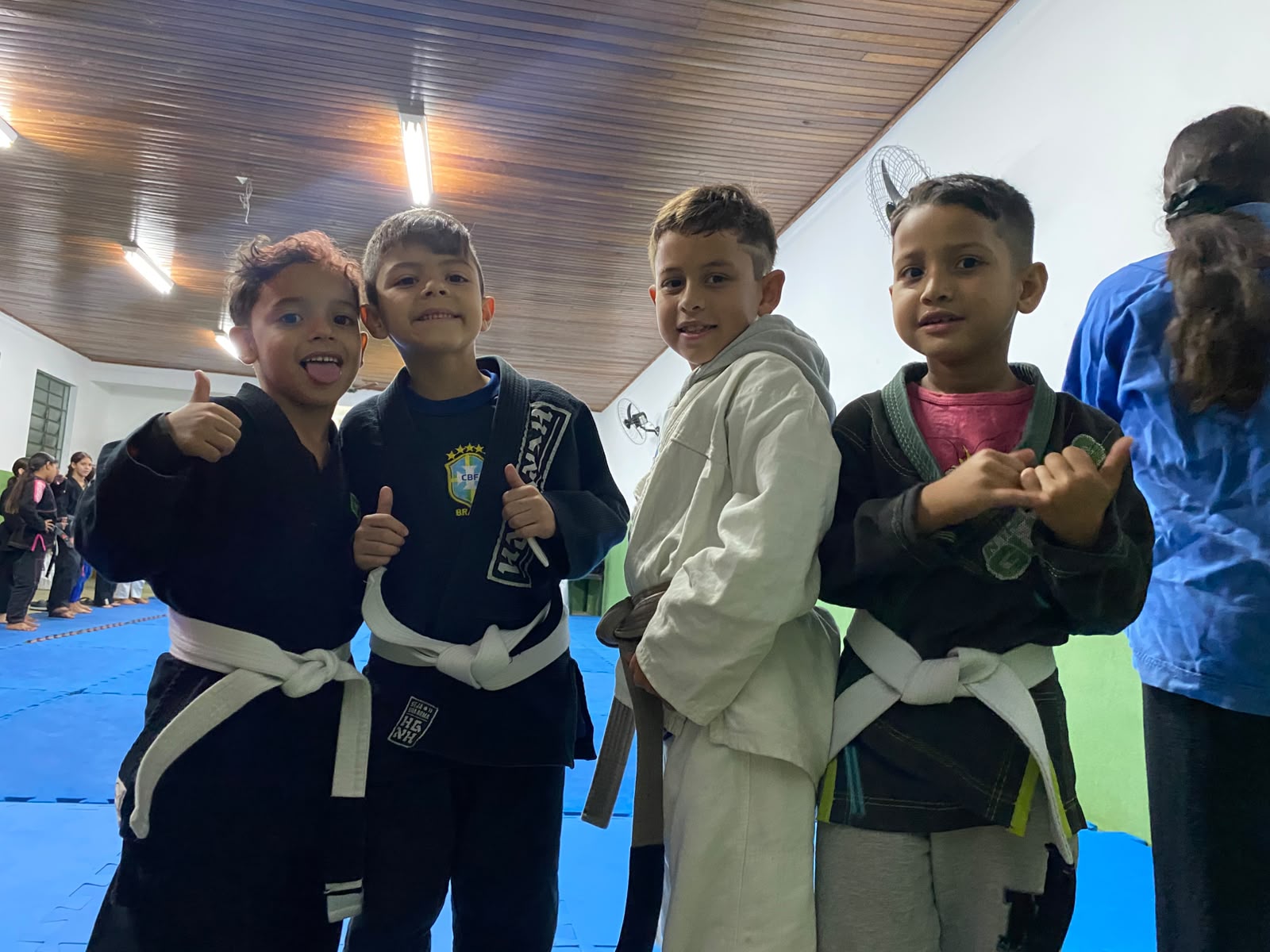 Quatro amigos kids sorrindo com kimonos no tatame