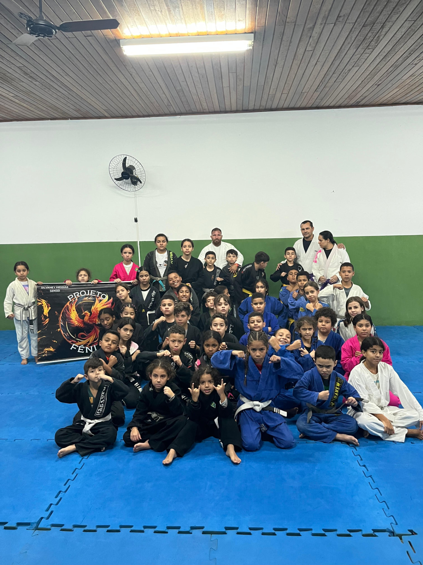 Turma kids reunida ao lado do banner oficial do Projeto Fênix