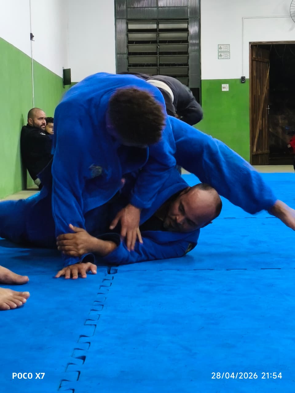 Dois atletas adultos treinando sparring de kimono azul