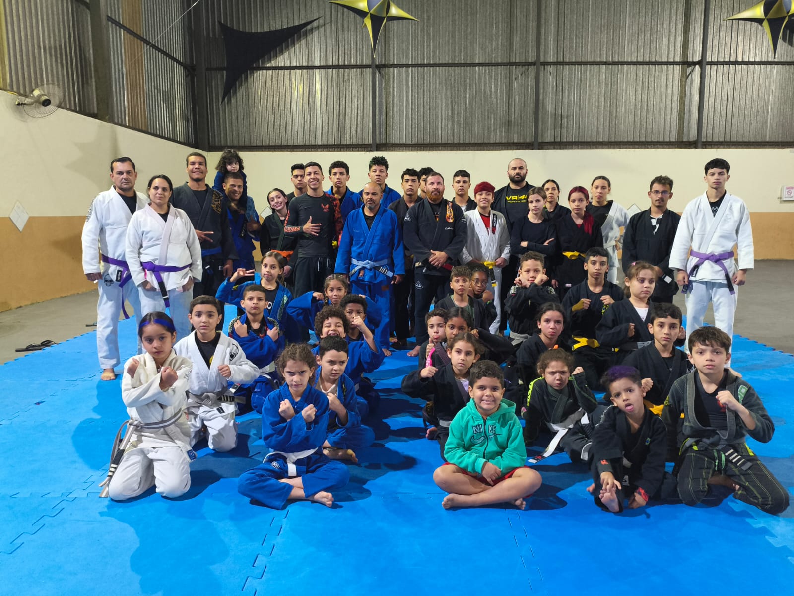 Foto oficial da equipe Projeto Fênix com kids e adultos no tatame azul