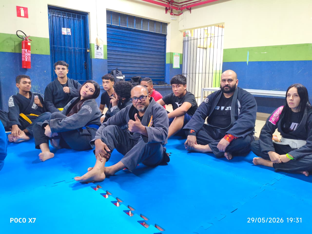 Grupo de alunos adultos sentados no tatame após o treino
