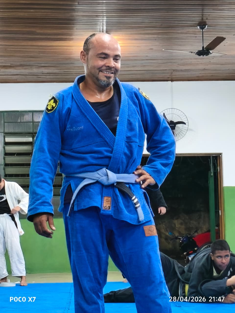 Aluno adulto faixa azul sorrindo no tatame