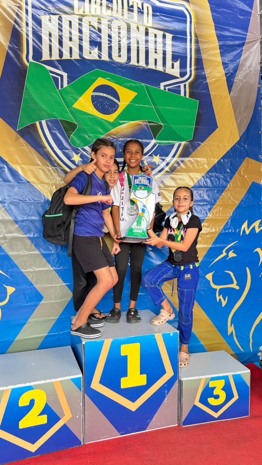 Quatro alunas kids no pódio segurando troféu do Circuito Nacional