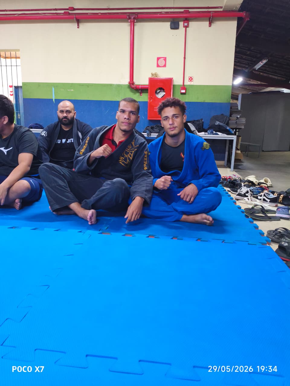 Alunos sentados no tatame durante intervalo do treino