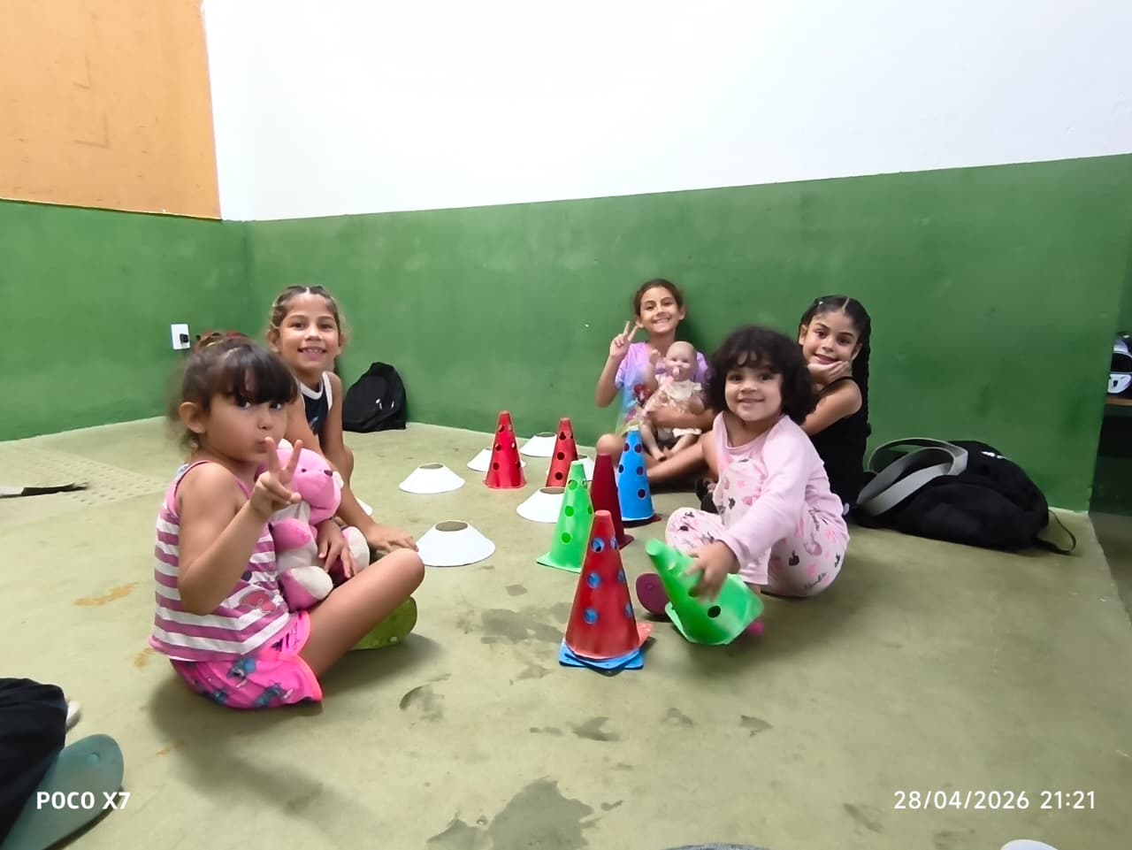 Meninas pequenas brincando com cones coloridos no tatame