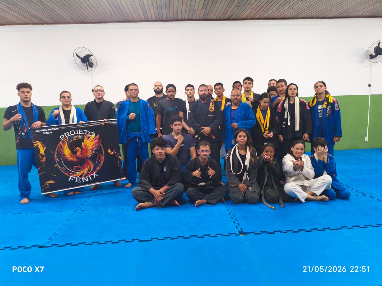 Equipe Projeto Fênix reunida no tatame ao lado da bandeira oficial