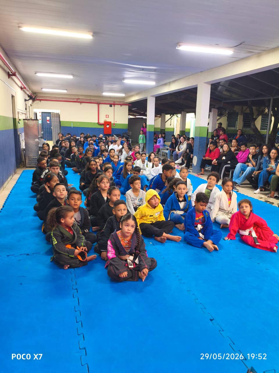 Vista ampla dos alunos kids sentados no tatame durante evento