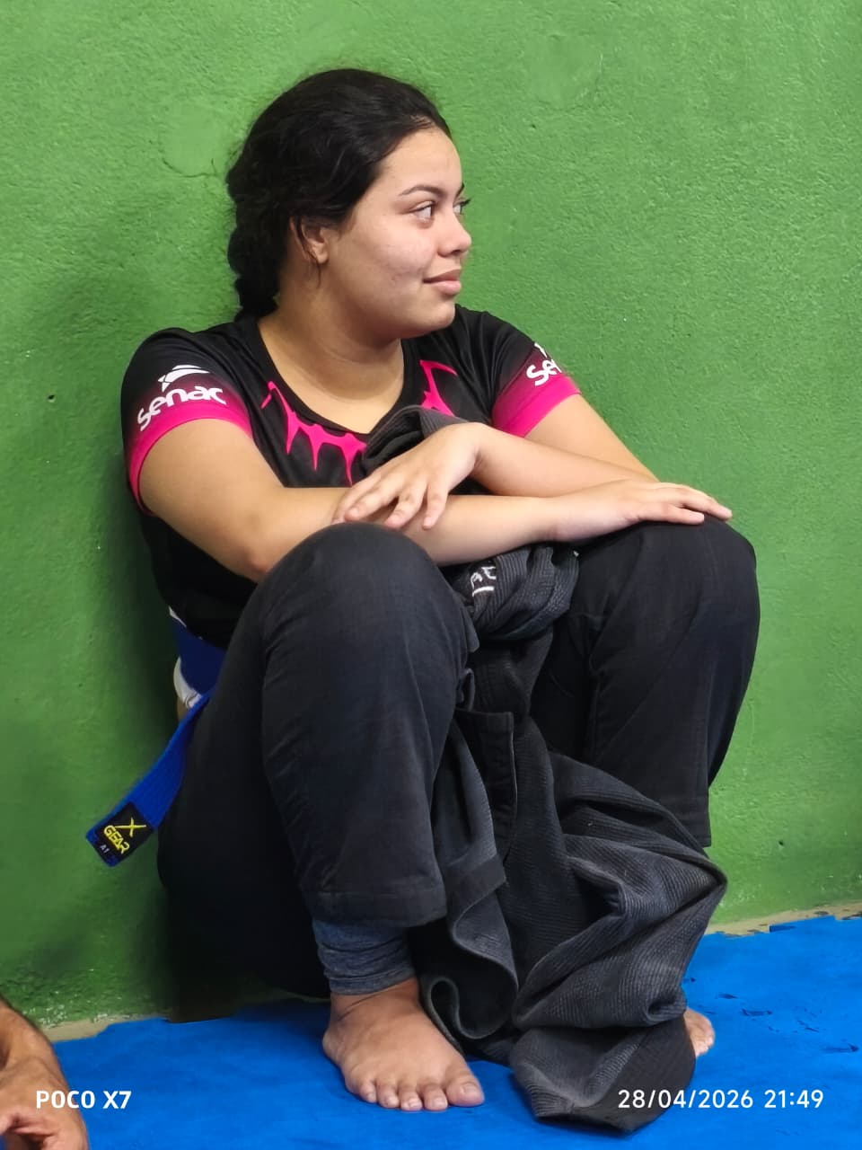 Aluna faixa azul sentada no tatame após treino